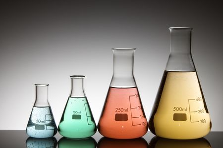 group of four flasks with colored liquid and a white backgroundの写真素材
