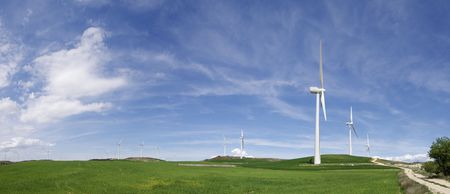 aligned windmills in green meadow with cloudy sky