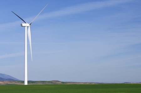 one modern windmill in a meadow with blue and cloudy sky