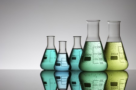 five flasks with colored liquid and a white background