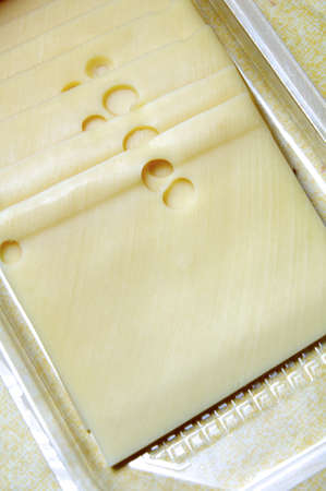 Given a few slices of Emmental cheese in plastic containerの写真素材