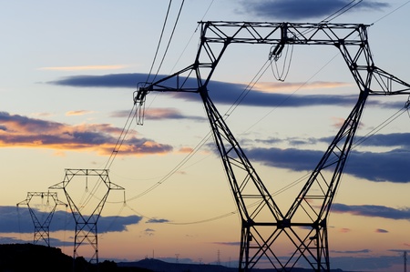 Electric poles against orange sky at sunrise