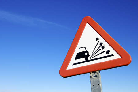road sign that warns of the danger of  loose gravel on the  roadの写真素材