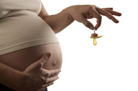 pregnant woman caressing  her belly and holding her  baby's pacifierの写真素材