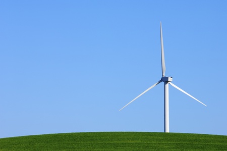 Modern windmill with blue sky in a green meadow