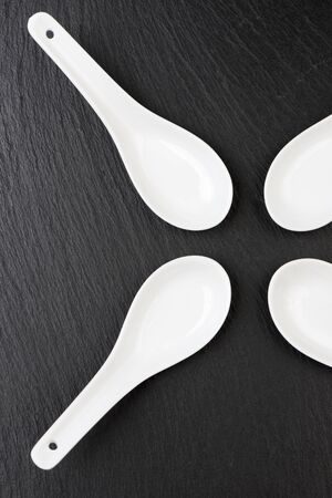 four small white spoons on a table slateの写真素材