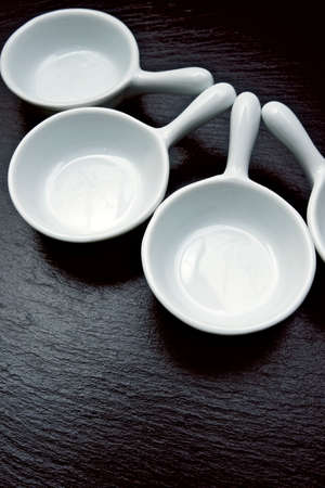 four small white spoons on a table slate