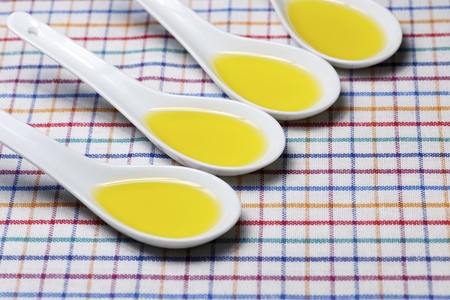Olive oil in a mall white spoons on a tableclothの写真素材