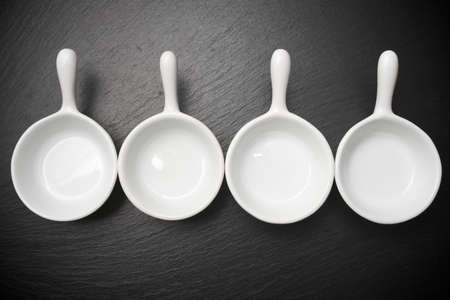 four small white spoons on a table slateの写真素材