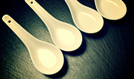 four small white spoons on a table slateの写真素材