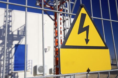 Warning sign high voltage with blue skyの写真素材
