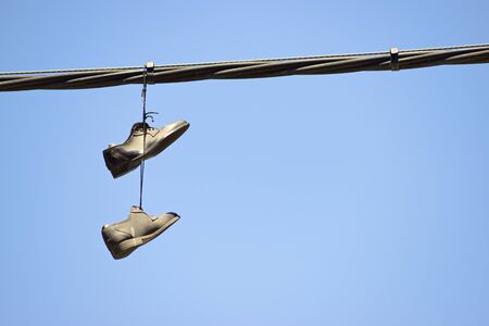 Pair of stylish shoes hanging from a cable.の写真素材