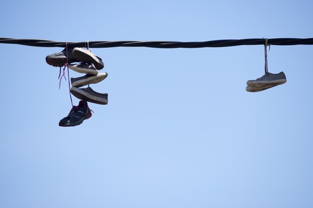 Old sneakers hanging from a cable.の写真素材