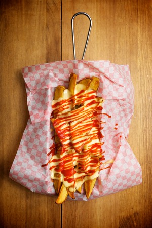Potatoes with spicy sauce on a checkered paper.