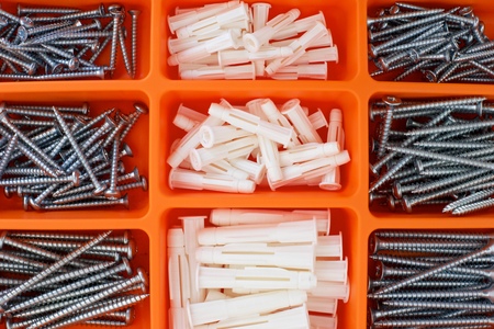 Screws and dowels on an orange box.