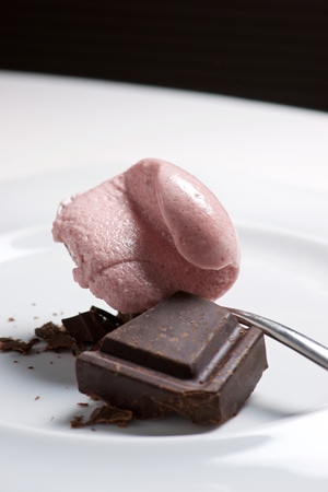 Strawberry ice cream with chocolat on a white plate.