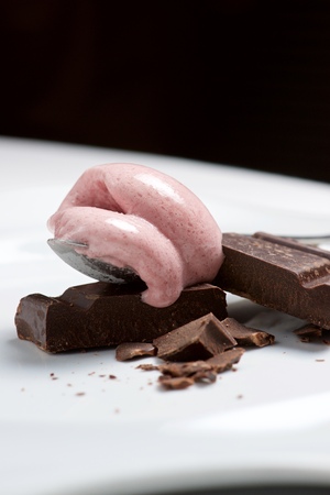 Strawberry ice cream with chocolat on a white plate.