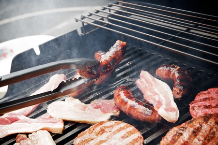 Preparation of a barbecue with sausages, burgers and bacon.の写真素材