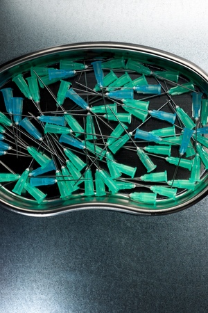 Group of needles for syringe on a metal tray.