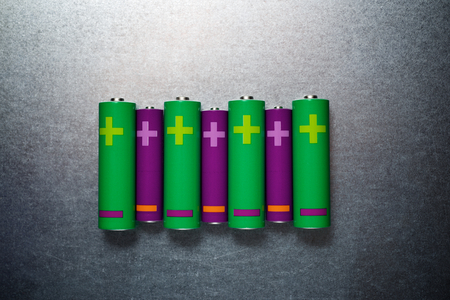 Eight batteries on a metal table.の写真素材