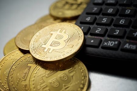 Bitcoins and a calculator on a metal table.