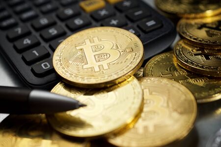 Bitcoins and a calculator on a metal table.の写真素材