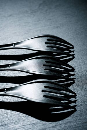 Disposable plastic cutlery on a black table.の写真素材