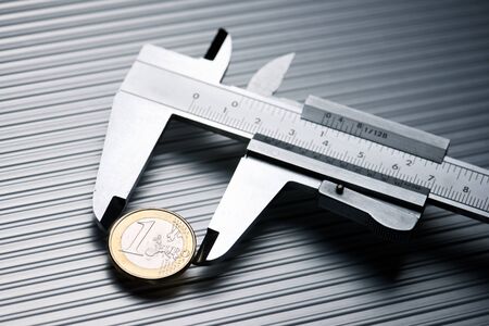 metal gauge measuring a one euro coin on a metal surface.の写真素材