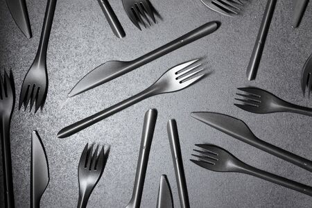 Disposable plastic cutlery on a black table.