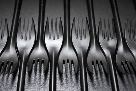 Disposable plastic cutlery on a black table.の写真素材