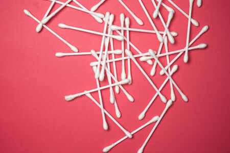Ear swabs on a pink table.