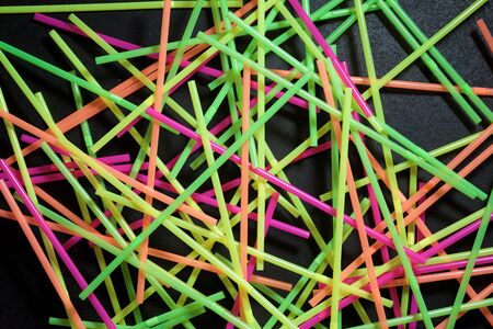 Drinking plastic straws on a black table.