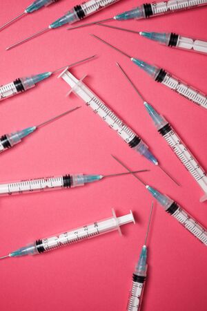 Close-up of a group of syringes on a pink table.の写真素材