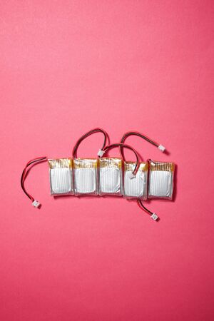 Drone batteries on a pink table.