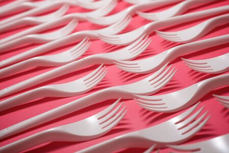 Disposable plastic cutlery on a pink table.の写真素材