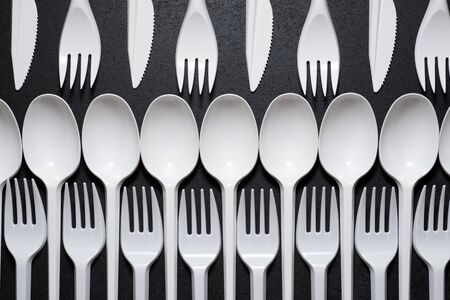 Disposable plastic cutlery on a black table.の写真素材