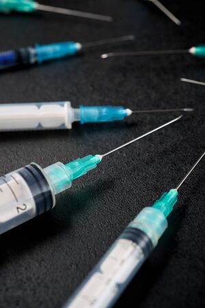Close-up of a group of syringes on a black table.の写真素材