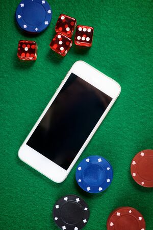 Smartphone and casino chips stacking on a green felt.の写真素材