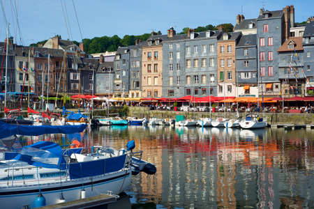 Honfleur, France - August 24, 2014: Boats docked in the harbor and tourists strolling during a sunny morning.のeditorial素材