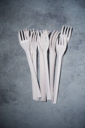 Disposable plastic cutlery on a stone table.の写真素材