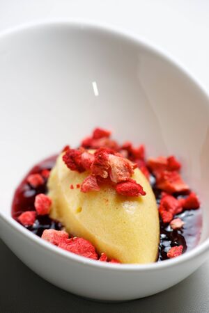 Peach ice cream with strawberry on a white bowl.の写真素材