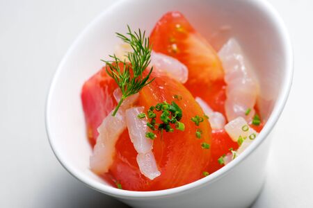 Tomato and cod in a small white bowl.の写真素材