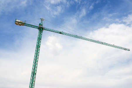 Green construction crane and sky with clouds.