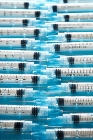 Close up of a group of syringes on a blue table.の写真素材