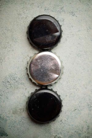 Collection of bottle caps on a stone table.