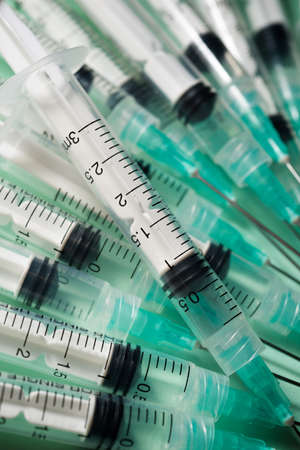 Close up of a group of syringes on a green table.
