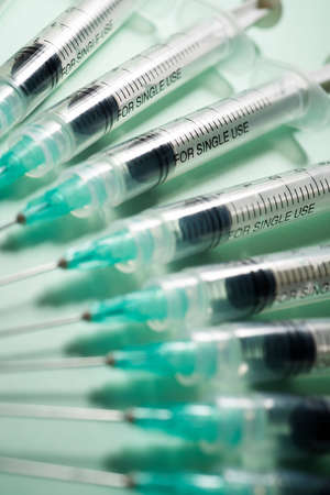 Close up of a group of syringes on a green table.の写真素材