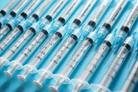 Close up of a group of syringes on a blue table.