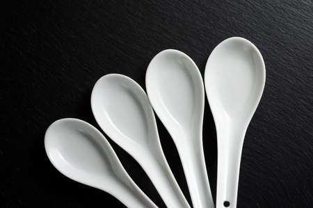 four small white spoons on a black slate table.の写真素材