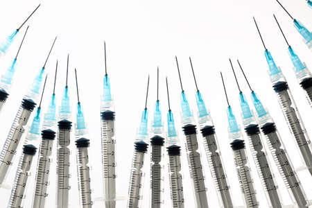 Close up of a group of syringes on a white backlit table.の写真素材